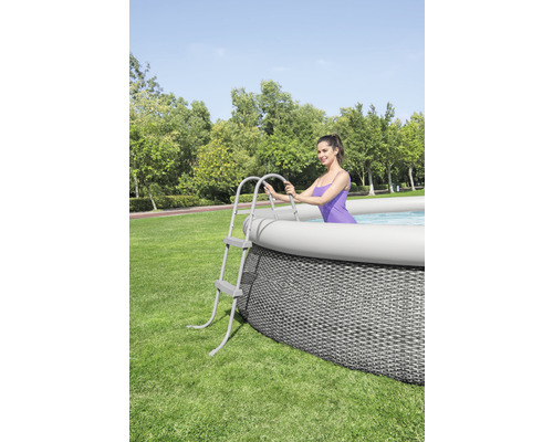 Ovanjordisk pool med stege och kvinna i trädgården