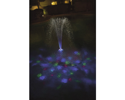 Belyst damm med fontän i mörkret