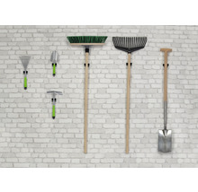 Olika trädgårdsredskap som krattor, spade och kvast hänger på en vägg.
