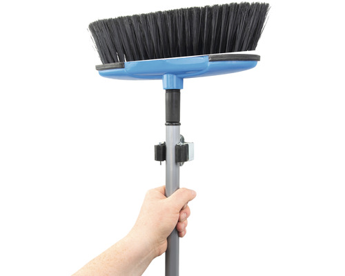 Hand håller sopborste med teleskopskaft