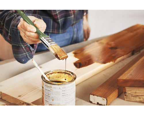 Applicering av träskyddslasyr med pensel på en träbräda