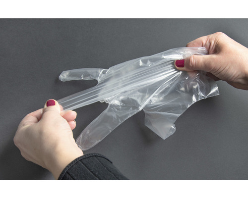 Kvinna tar på sig en transparent engångshandske