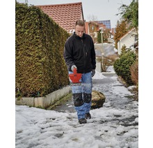 Man tar bort snö från en trottoar med en snöslunga