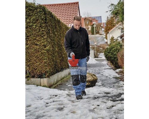 Man tar bort snö från en trottoar med en snöslunga