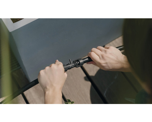 En person ansluter en bevattningsslang till en koppling.