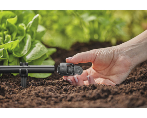 Detaljbild av en person som fäster en kontakt till ett bevattningssystem i trädgården