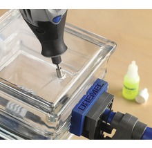 Dremel multiverktyg borrar ett hål i ett glasblock som är fäst med en Dremel skruvtving