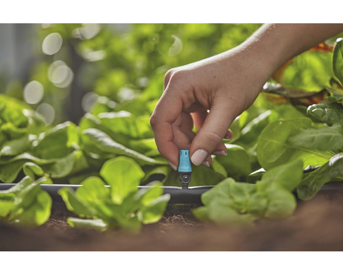Närbild av en hand som justerar ett bevattningssystem i trädgården