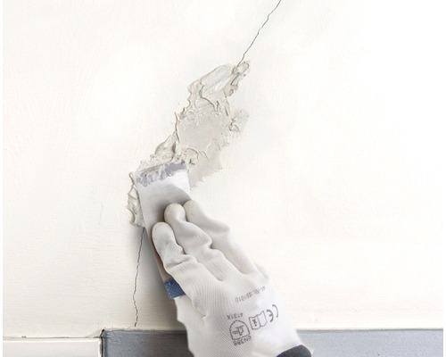 En spricka i en vägg fylls med en spackel.