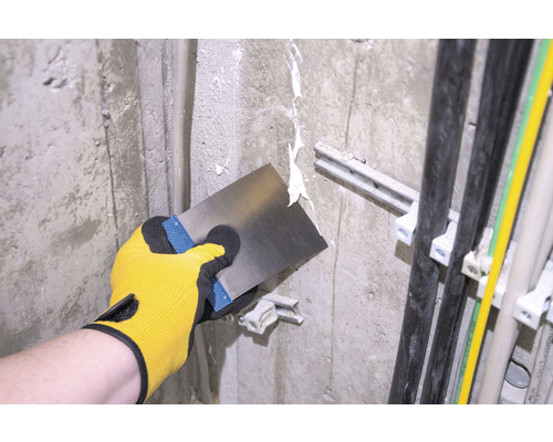 Hantverkare spacklar en vägg med en spackel.