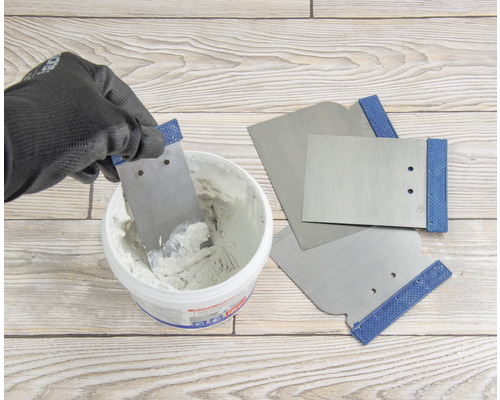 Spackel tas upp ur en hink med en spackelspade, fler spacklar ligger redo