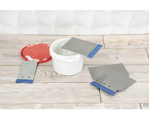 Spackel i en hink med spacklar på ett trägolv