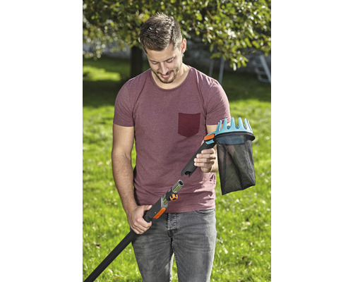 En man ansluter en fruktplockare till ett teleskopskaft i trädgården.