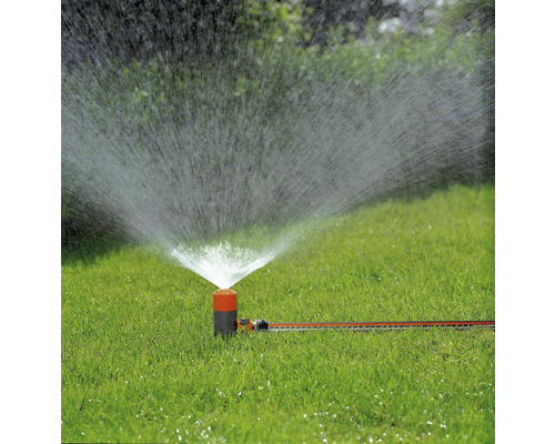 Grässpridare i drift på en grön gräsmatta