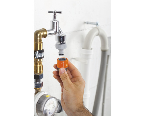 Hand fäster Gardena-adapter på vattenkran för trädgårdsbevattning