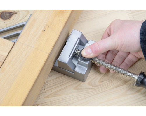 En person fixerar två träbitar med en vinkelklämma.