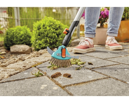 Fogborste med teleskopskaft som används på gatsten för att ta bort ogräs