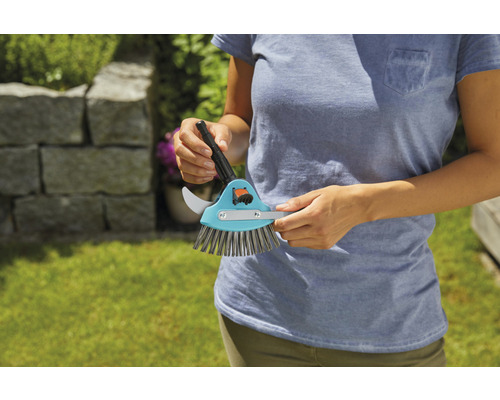 En person håller i en fogskrapa med fogskrapa och borste.