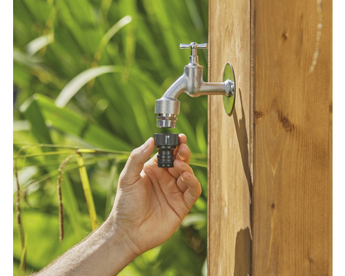 En hand ansluter en krankoppling till en trädgårdskran.