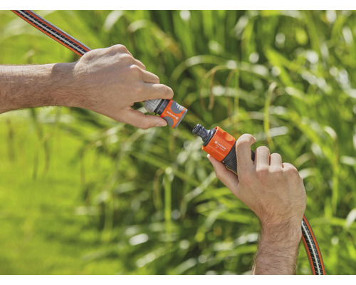 Två händer ansluter en trädgårdsslang med en slangkoppling.