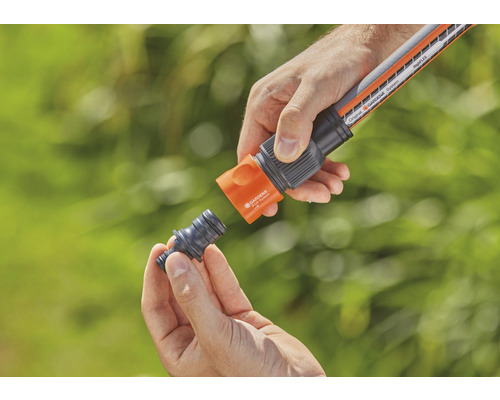 Person kopplar trädgårdsslang med slangkoppling