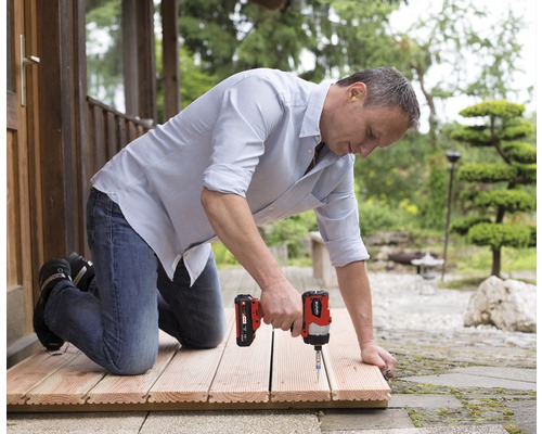 Man knäböjer på en träaltan och arbetar med en sladdlös mutterdragare för att fästa brädor