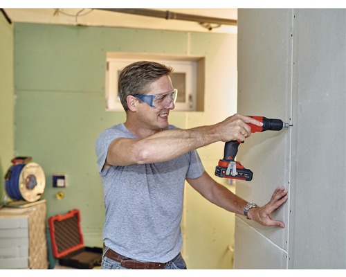 Man skruvar gipsvägg med batteridriven skruvdragare