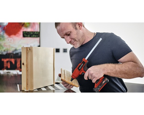 Man använder en limpistol för att foga samman trädelar.