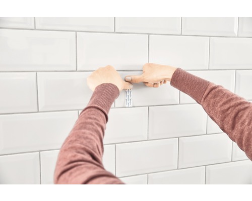 Fästa en självhäftande krok på vita kakelplattor