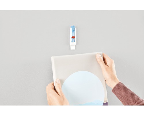 Person hänger bild med bildkrok på väggen