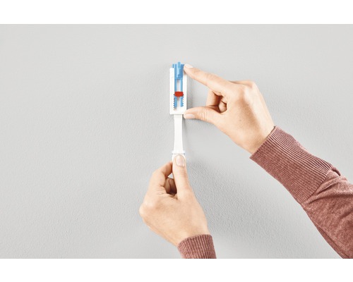 En person använder ett verktyg för att markera borrhål på en vägg.