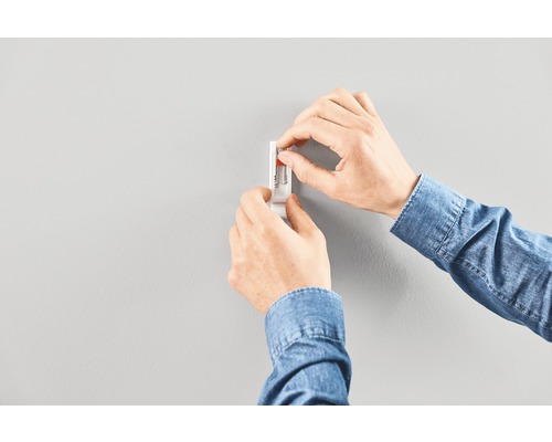 Person monterar väggfäste med plugg på en vägg.