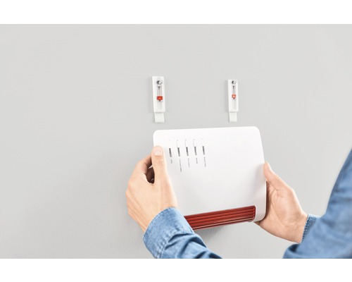 Person som monterar en vit router med självhäftande krokar på väggen