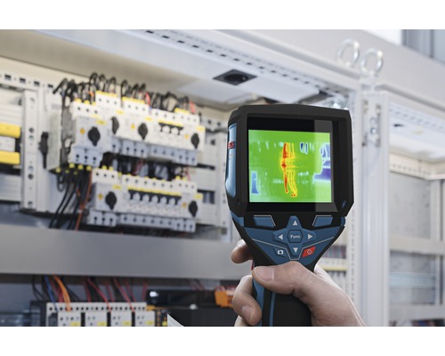 En värmekamera används framför ett elskåp för att mäta värme.