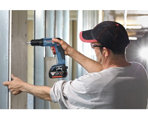 Hantverkare skruvar gipsskiva på metallstomme med en sladdlös gipsskruvdragare