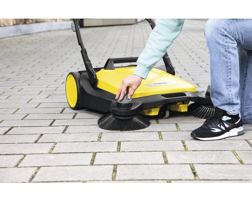 Gul Kärcher sopmaskin i bruk på gatstenar