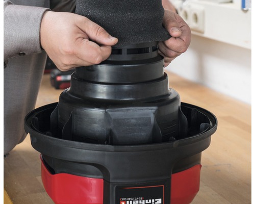 En man sätter ett filterskum på en Einhell dammsugare.
