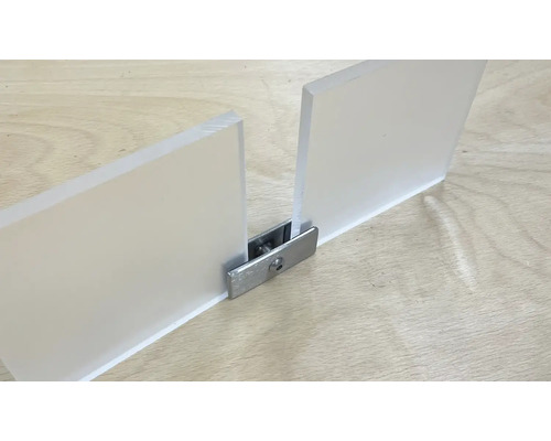 Två akrylglasskivor förbundna med en metallkoppling på en träyta