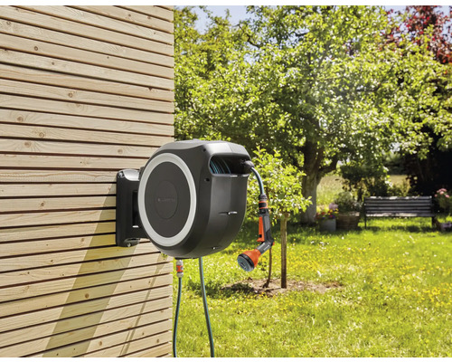 Trädgårdsslangbox med slang och spruta för trädgårdsbevattning monterad på en trävägg