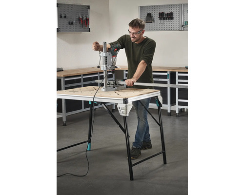 Man arbetar med en borrmaskin vid en arbetsbänk i en verkstad.