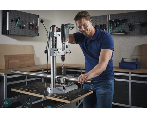 Man borrar ett rör med en bordsborrmaskin i en verkstad.