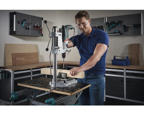 Man som arbetar med en bänkborrmaskin på en träbit i en verkstad
