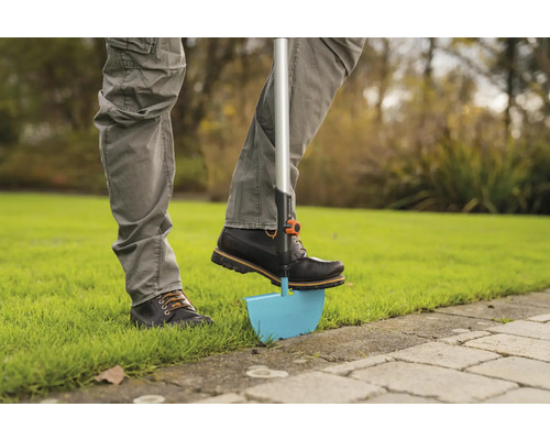 Person använder en gräskantstickare i trädgården.