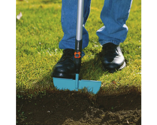 Person använder en gräskantskärare i trädgården.