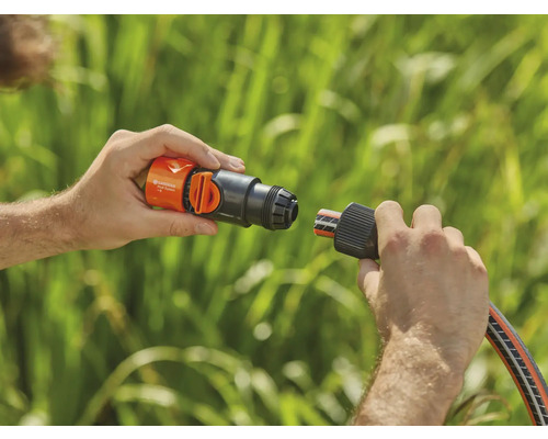 En person ansluter en Gardena slangkontakt till en krananslutning.