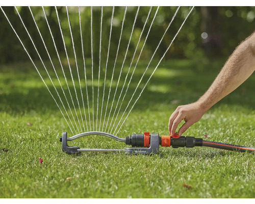 Grässpridare vattnar gräsmattan med vattenstrålar