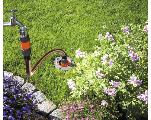 Vattenkran ansluten till en underjordisk vattenanslutning i trädgården.