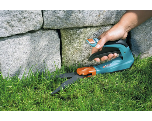 Gardena grässax klipper gräs nära en stenmur