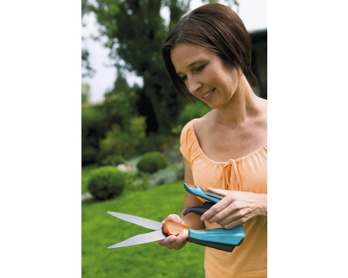 Kvinna tittar på grässax mot trädgårdsbakgrund