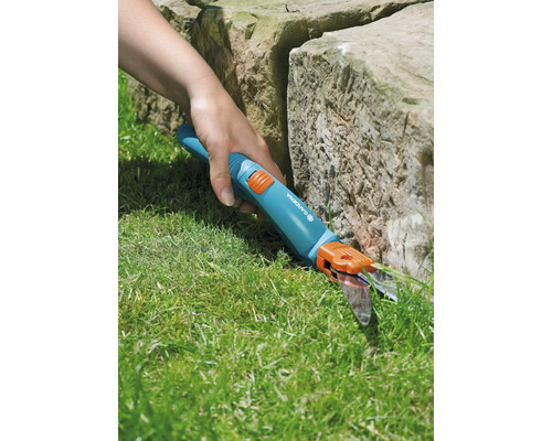 Trädgårdssax i bruk för att klippa gräskanter vid en sten